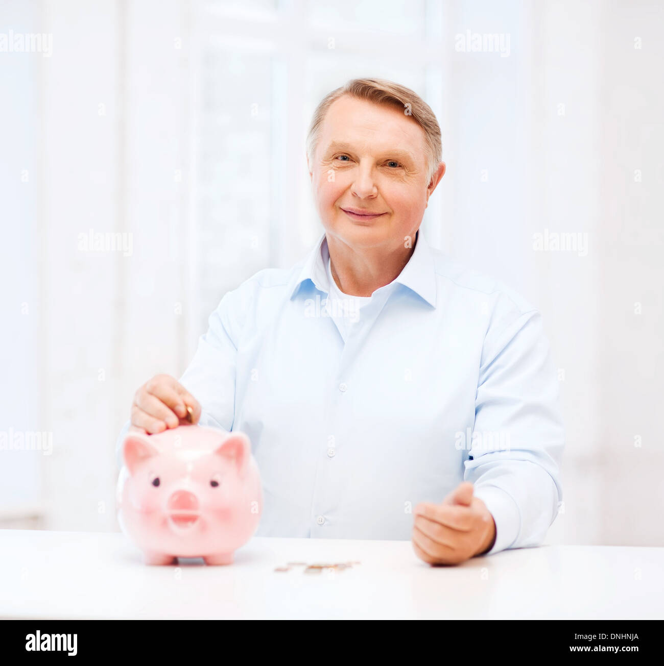 Il vecchio uomo di mettere moneta nella grande salvadanaio Foto Stock