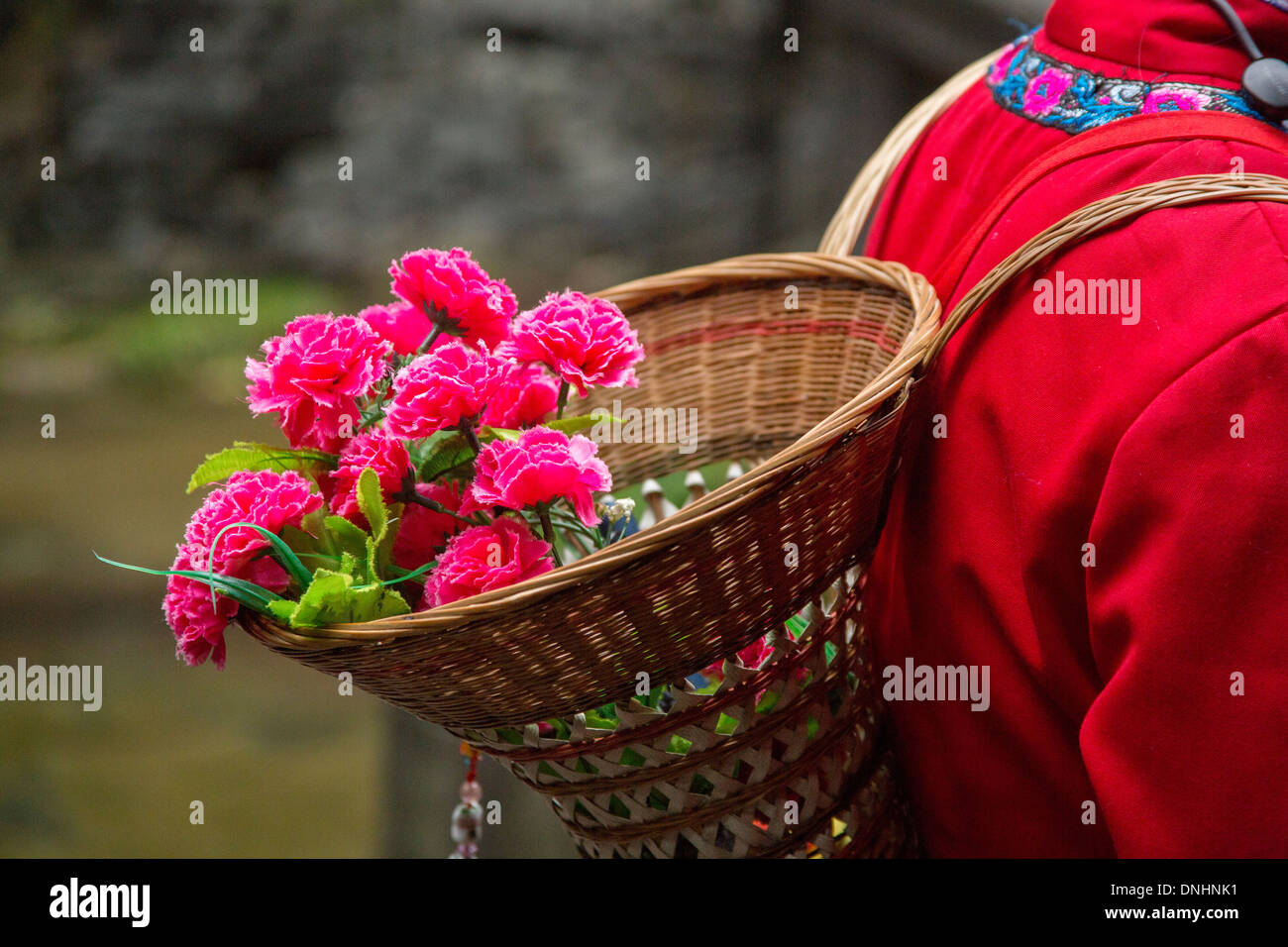 La guida turistica di artificiale che trasportano fiori di carta in un cestino sul suo indietro nel villaggio di Fengdu Cina Foto Stock