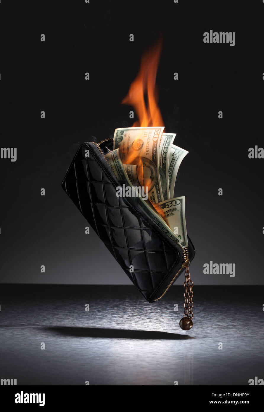 Un marrone portafoglio in pelle riempito con carte di credito e denaro sul fuoco. Foto Stock