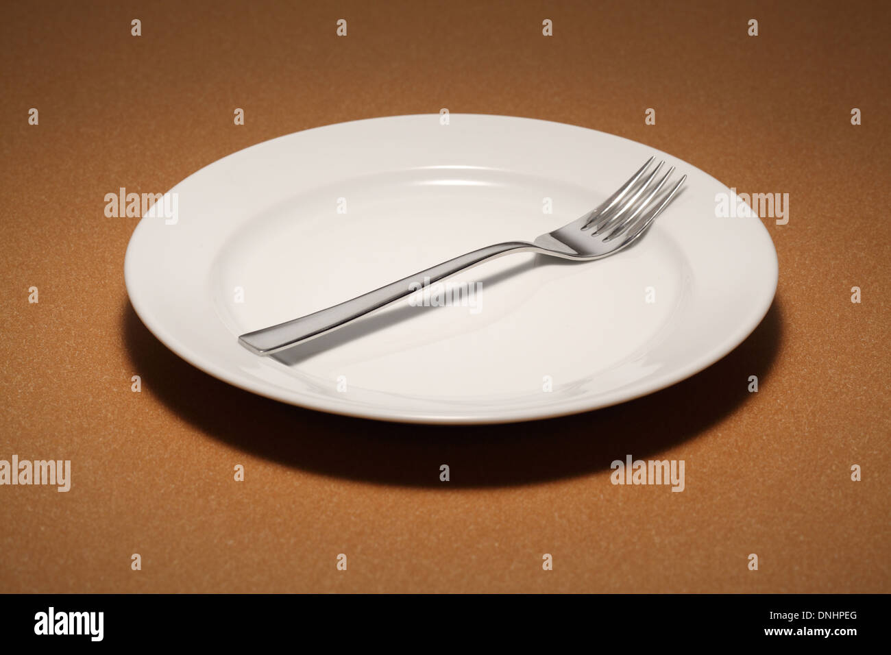 Una forcella da pranzo su una bianca vuota piastra da pranzo. Foto Stock