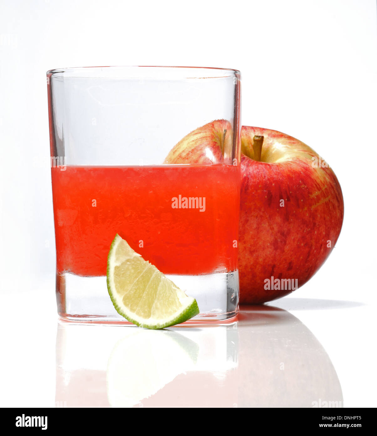 Un vivace cocktail drink in un bicchiere con un cuneo di calce e tutta una mela rossa Foto Stock