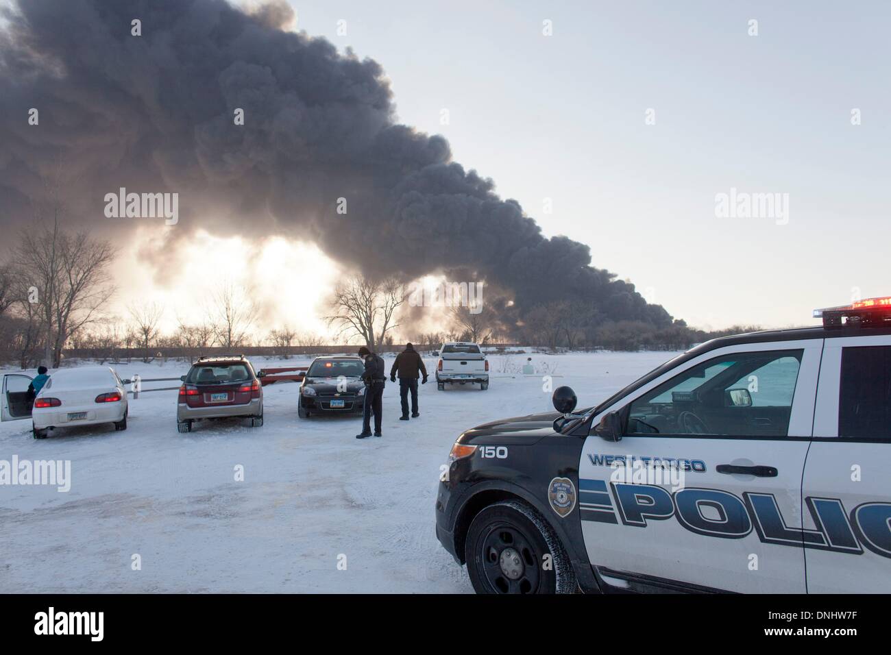 Casselton, il Dakota del Nord, Stati Uniti d'America. 30 Dic, 2013. I funzionari di polizia il controllo del traffico in prossimità di un deragliato BNSF treno masterizza appena ad ovest di Casselton. Almeno sette vetture su 106 auto-treno esploso in fiamme dopo l'incidente con diversi esplodendo in enormi palle di fuoco. Credito: Dave Arntson/ZUMAPRESS.com/Alamy Live News Foto Stock