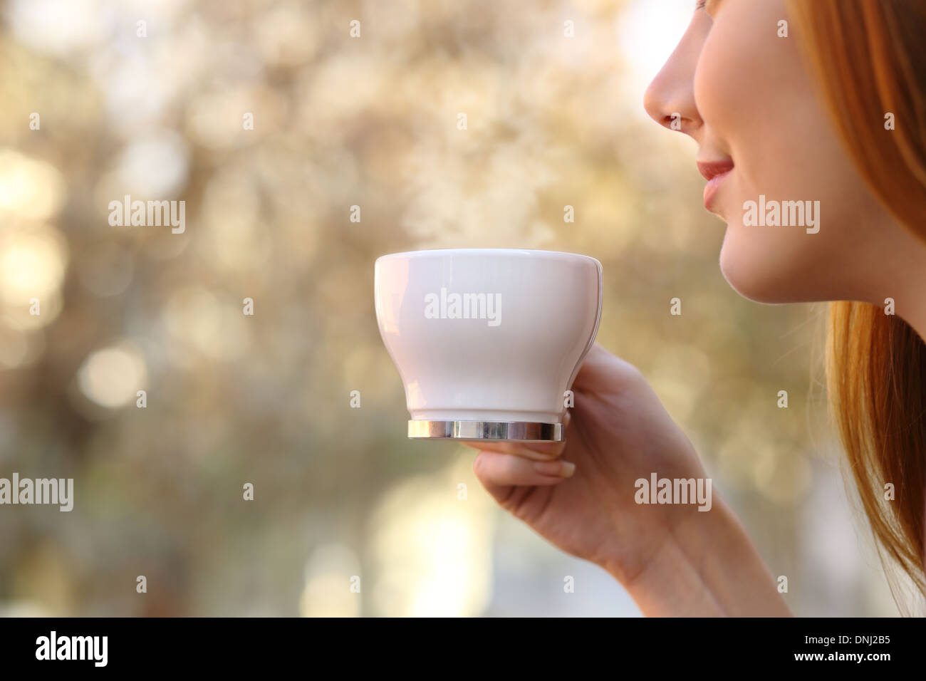 In prossimità di una donna in possesso di una tazza di caffè con una sfocatura dello sfondo caldo Foto Stock