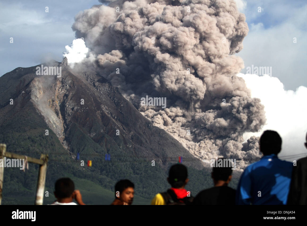 Villaggio Tigapancur, nel nord di Sumatra, Indonesia . 31 Dic, 2013. Il monte Sinabung produca fumo piroclastici è visto dal villaggio Tigapancur su dicembre 31, 2013 in Karo distretto, nel nord di Sumatra, Indonesia. Il monte Sinabung, che è stata in modo intermittente in eruzione dal mese di settembre ha eruttato otto volte in poche ore nella giornata di domenica. I funzionari hanno riferito di rocce che piovono su di una grande area, costringendo migliaia di persone a fuggire dalle loro case. Il governo indonesiano ha chiamato per le persone che vivono entro cinque chilometri (3.1 miglia) del vulcano, sulla punta nord dell isola di Sumatra, per evacuare le loro case. © Foto Stock