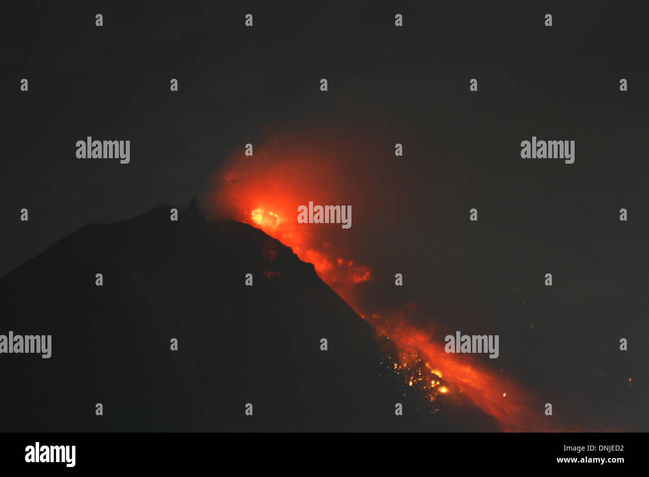 Villaggio Tigapancur, Karo distretto, nel nord di Sumatra, Indonesia. Il 30 dicembre 2013. Il monte Sinabung produca fumo piroclastici è visto dal villaggio Tigapancur. Il monte Sinabung, che è stata in modo intermittente in eruzione dal mese di settembre ha eruttato otto volte in poche ore nella giornata di domenica. I funzionari hanno riferito di rocce che piovono su di una grande area, costringendo migliaia di persone a fuggire dalle loro case. Credito: Ade Sinuhaji/Alamy Live News Foto Stock