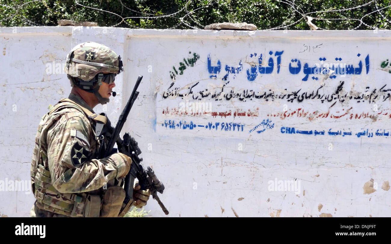 Un esercito statunitense pattuglie di soldati passato un segno in arabo script durante un funzionamento con il Provincial Reconstruction Team Farah Luglio 2, 2013 in provincia di Farah, Afghanistan. Foto Stock