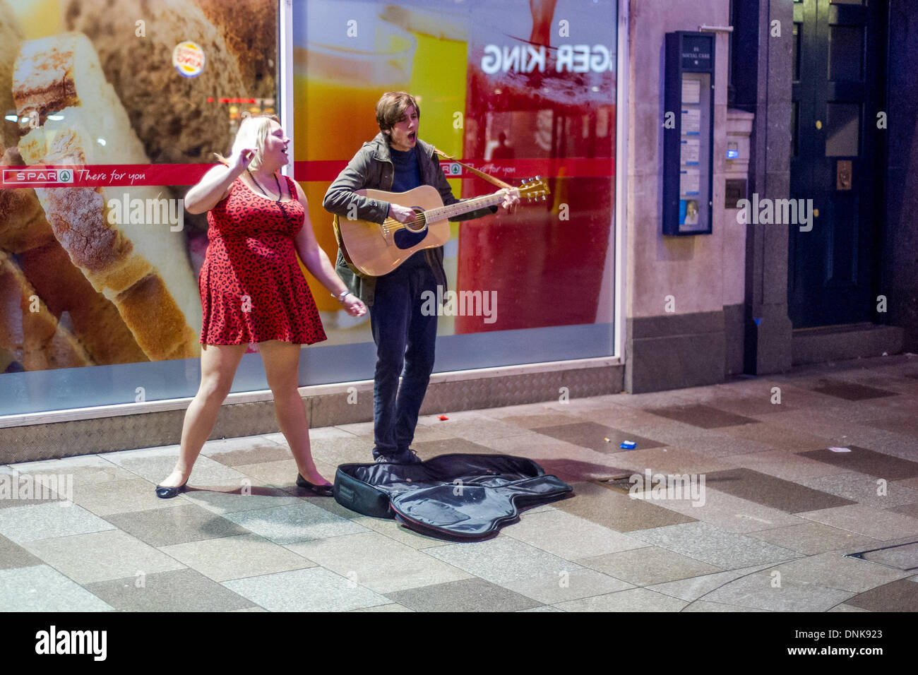 Cardiff, Galles, UK. Il 31 dicembre 2013. Una donna balli mentre un busker riproduce un brano fuori del longherone e Burger King. Le persone si sono riunite nella capitale gallese per vedere all'inizio del 2014. Credito: Polly Thomas / Alamy Live News Foto Stock