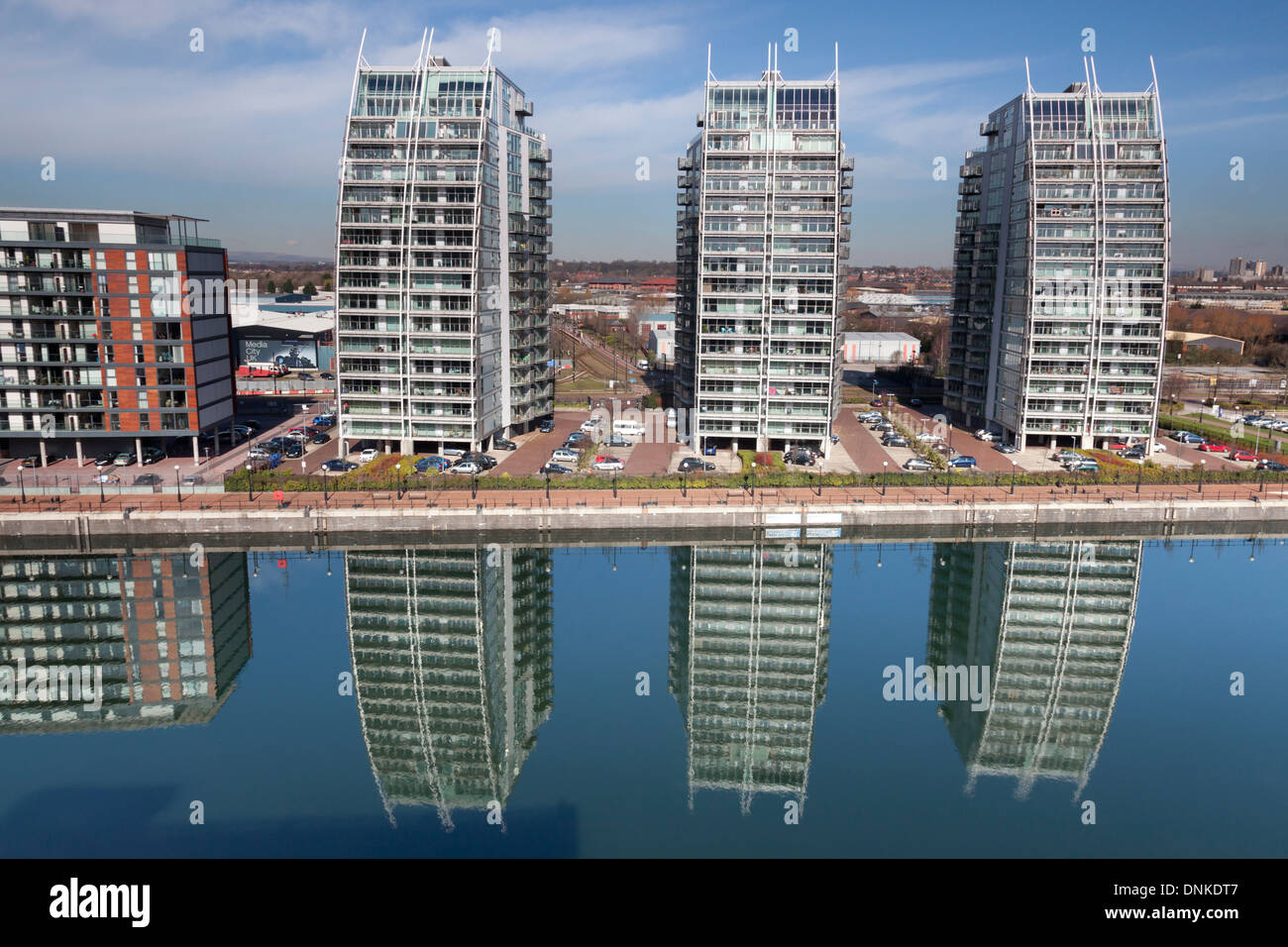 Le facciate curve dei tre edifici NV riflessi nell'acqua del bacino di Huron a Salford Quays Foto Stock