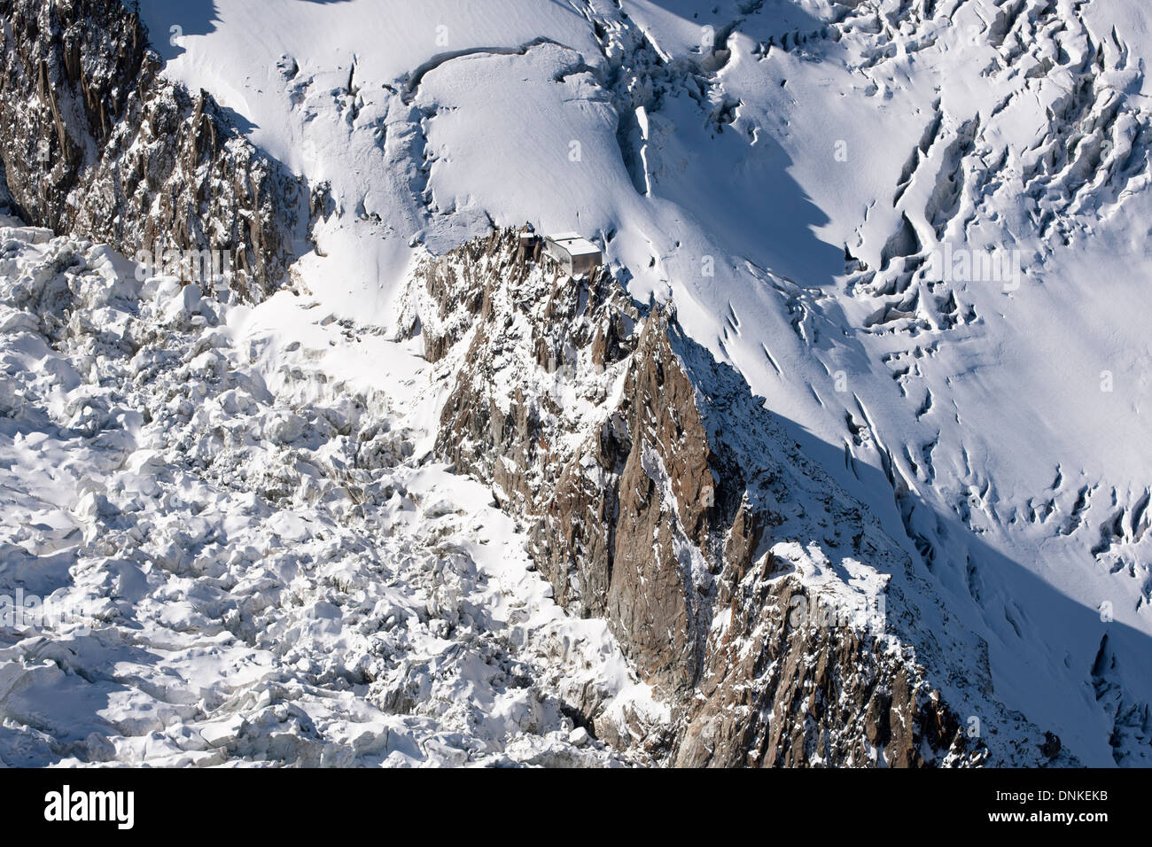 VISTA AEREA. Capanna arroccata precariamente su aghi di granito e circondata da ghiacciai con profondi crepacci. Rifugio Grands Mulets, Chamonix, Francia. Foto Stock