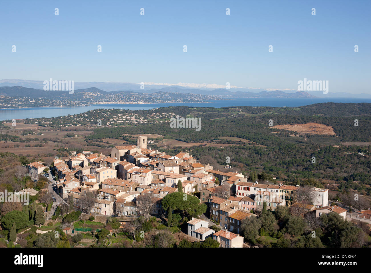 VISTA AEREA. Arroccato borgo medievale che domina il Golfo di Saint-Tropez e le montagne innevate del Mercantour in lontananza. Gassin, Var, Francia. Foto Stock