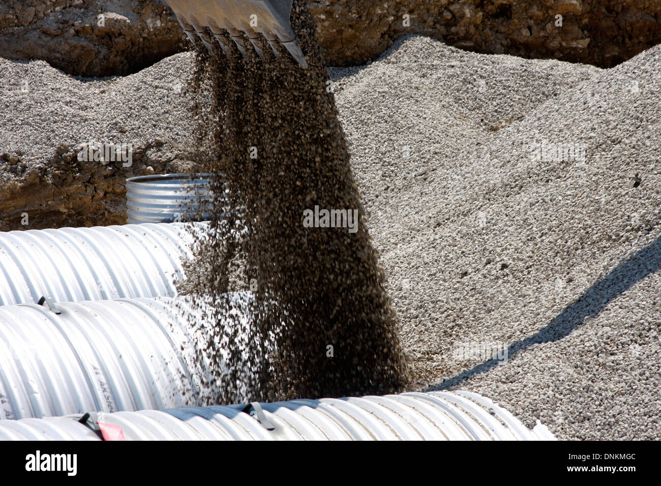 Il riempimento di ghiaia essendo collocato attorno all acqua piovana storage cisterne metalliche utilizzate per la qualità delle acque Foto Stock