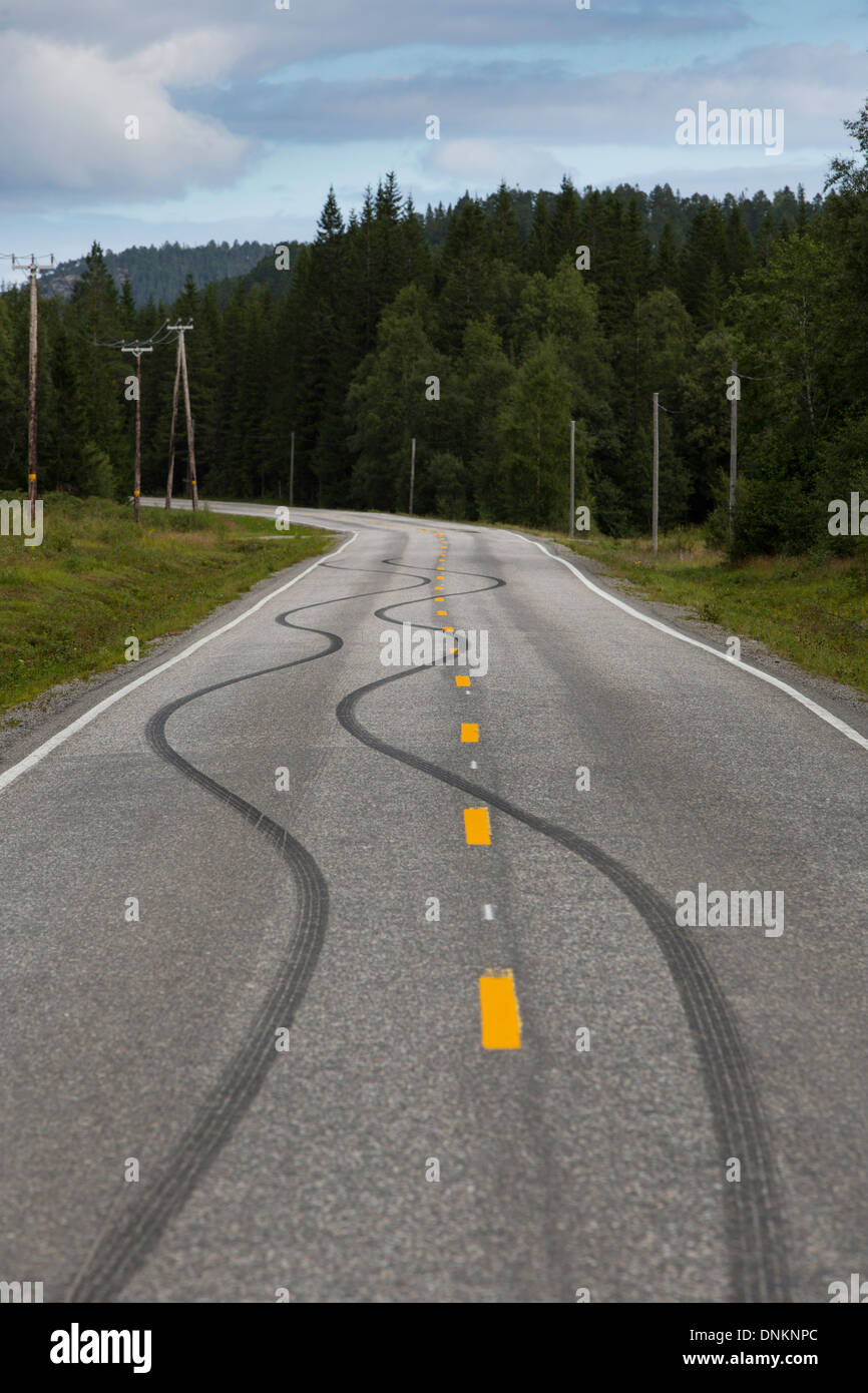 Pattino di gomma segni sulla strada che attraversa la linea centrale, probabilmente creato come espressione di noia dalla gioventù locale Foto Stock