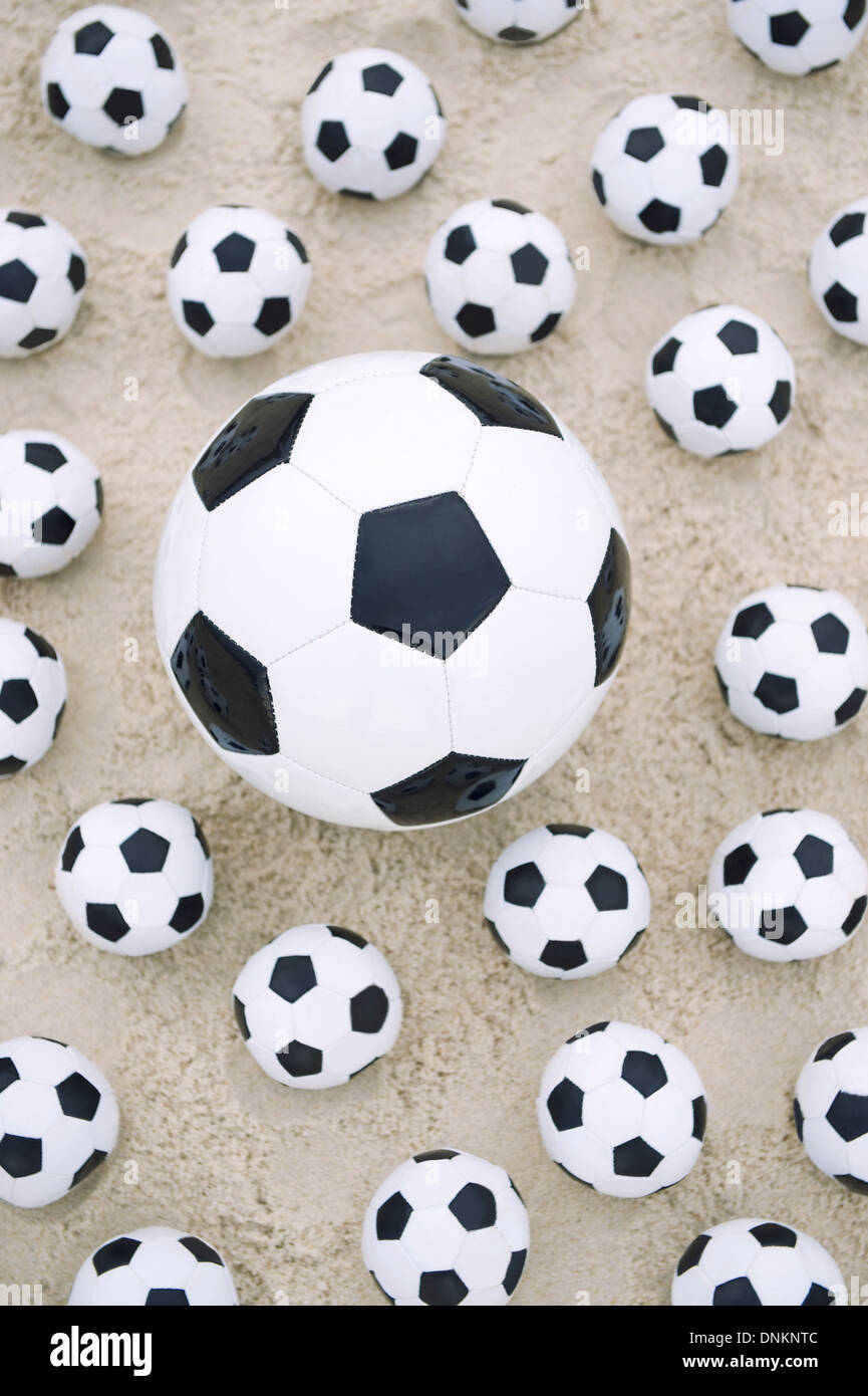 Molti piccoli palloni da calcio circondano grande pallone da calcio  brasiliano sulla spiaggia di sabbia Foto stock - Alamy