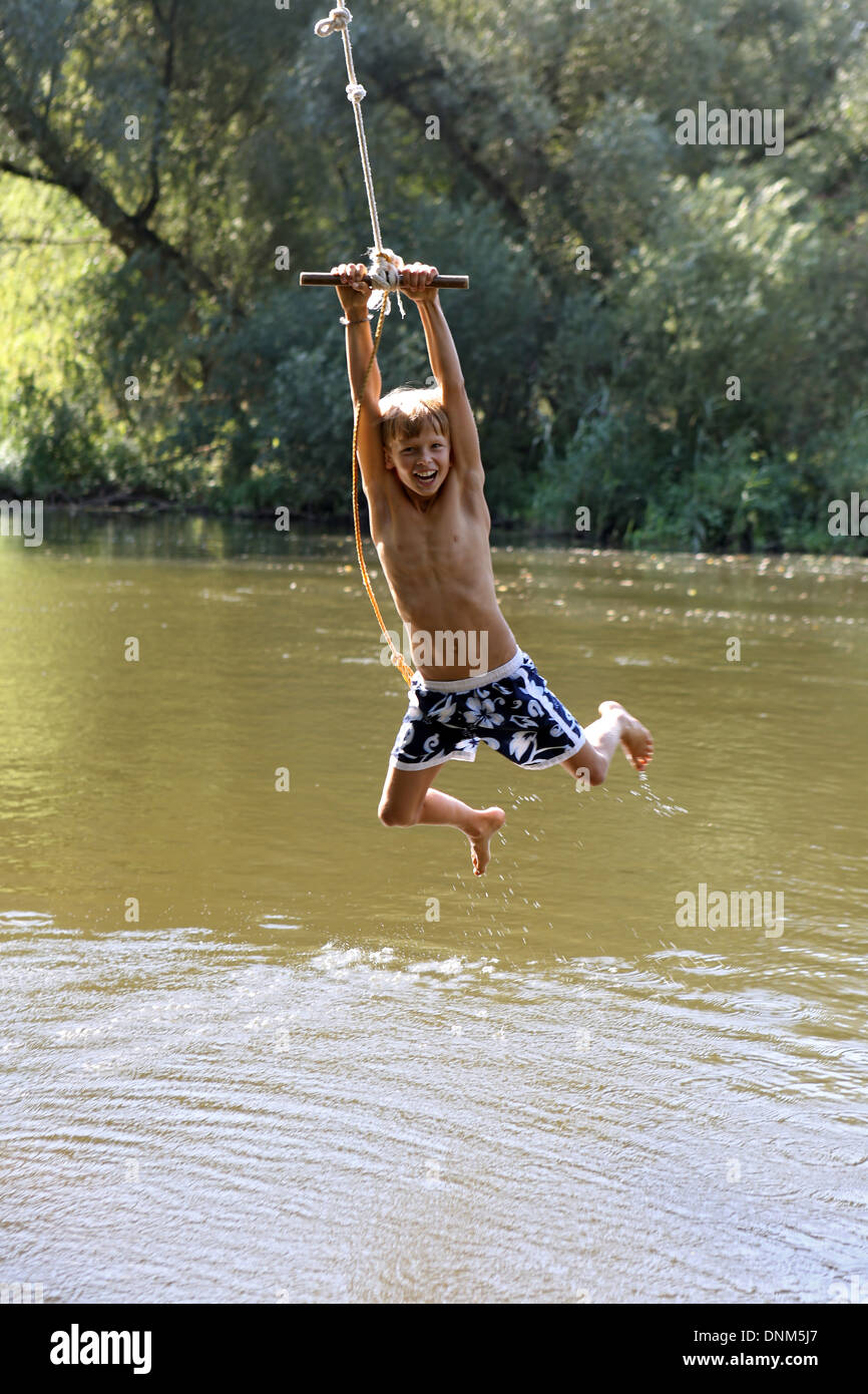 Briescht, Germania, ragazzo basculante in una corda sopra le acque del fiume Sprea Foto Stock
