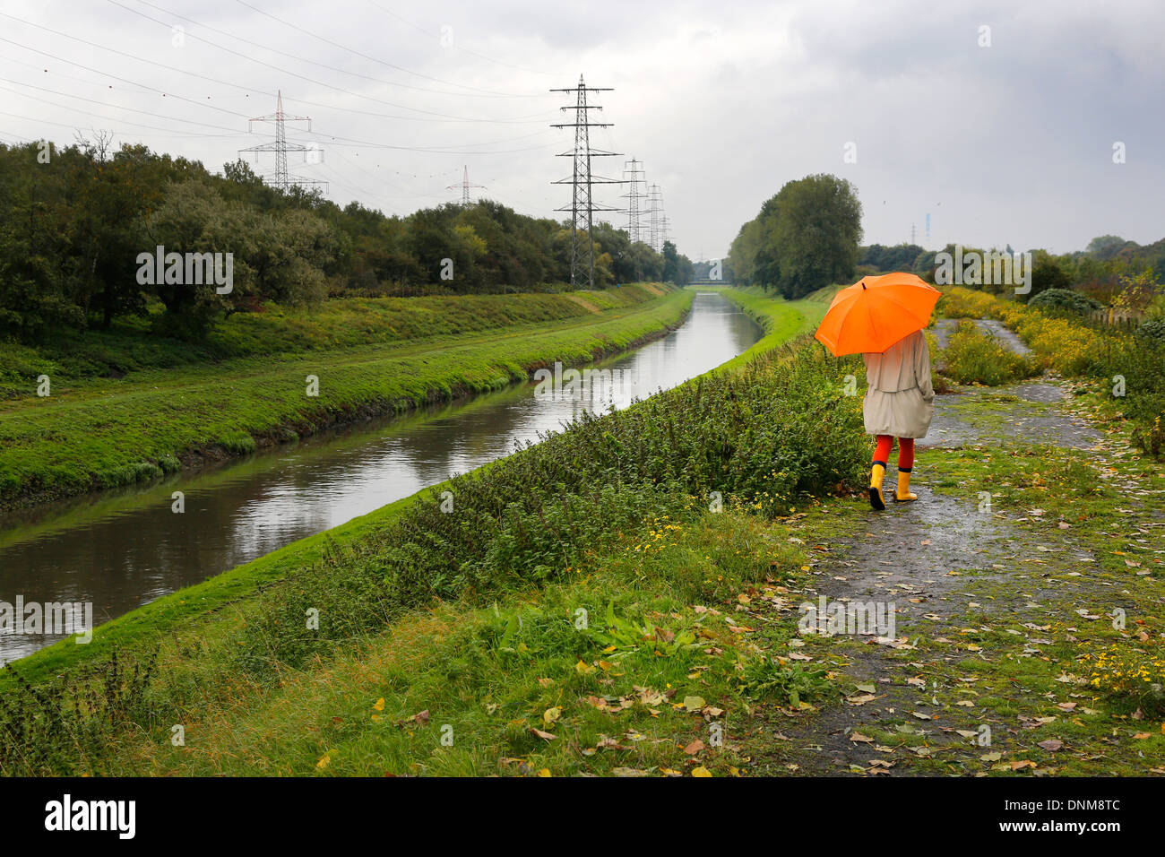 Oberhausen, Germania, una giovane donna cammina sotto la pioggia con ombrello a piedi lungo l Emscher Foto Stock