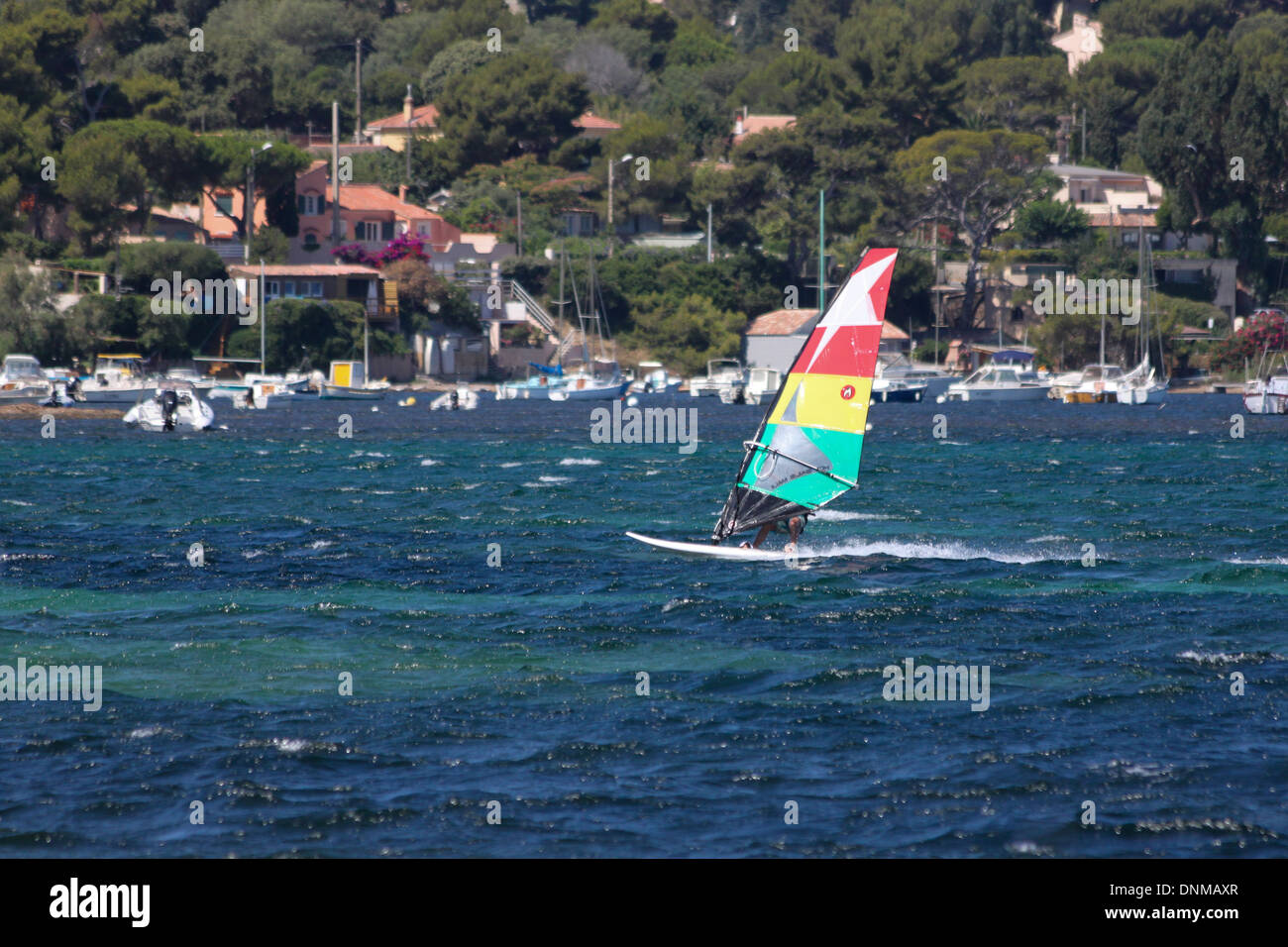 Una fotografia di un windsurf con una verde, giallo e il Red Sail contro uno sfondo di barche. Prese a hyeres, Francia. Foto Stock