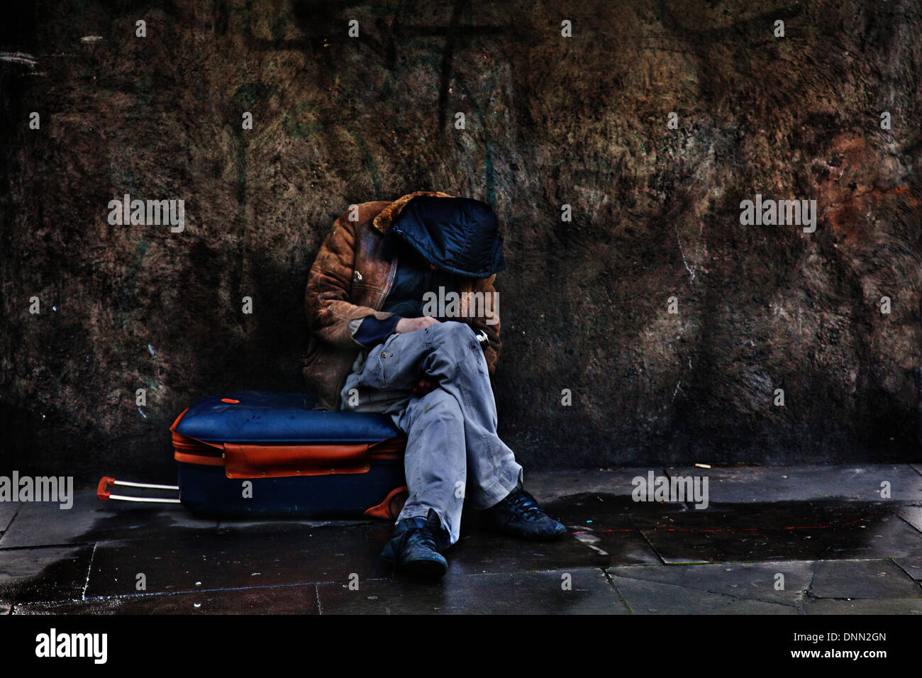Senzatetto uomo addormentato sulla sua valigia, Warren Street, Londra Foto Stock