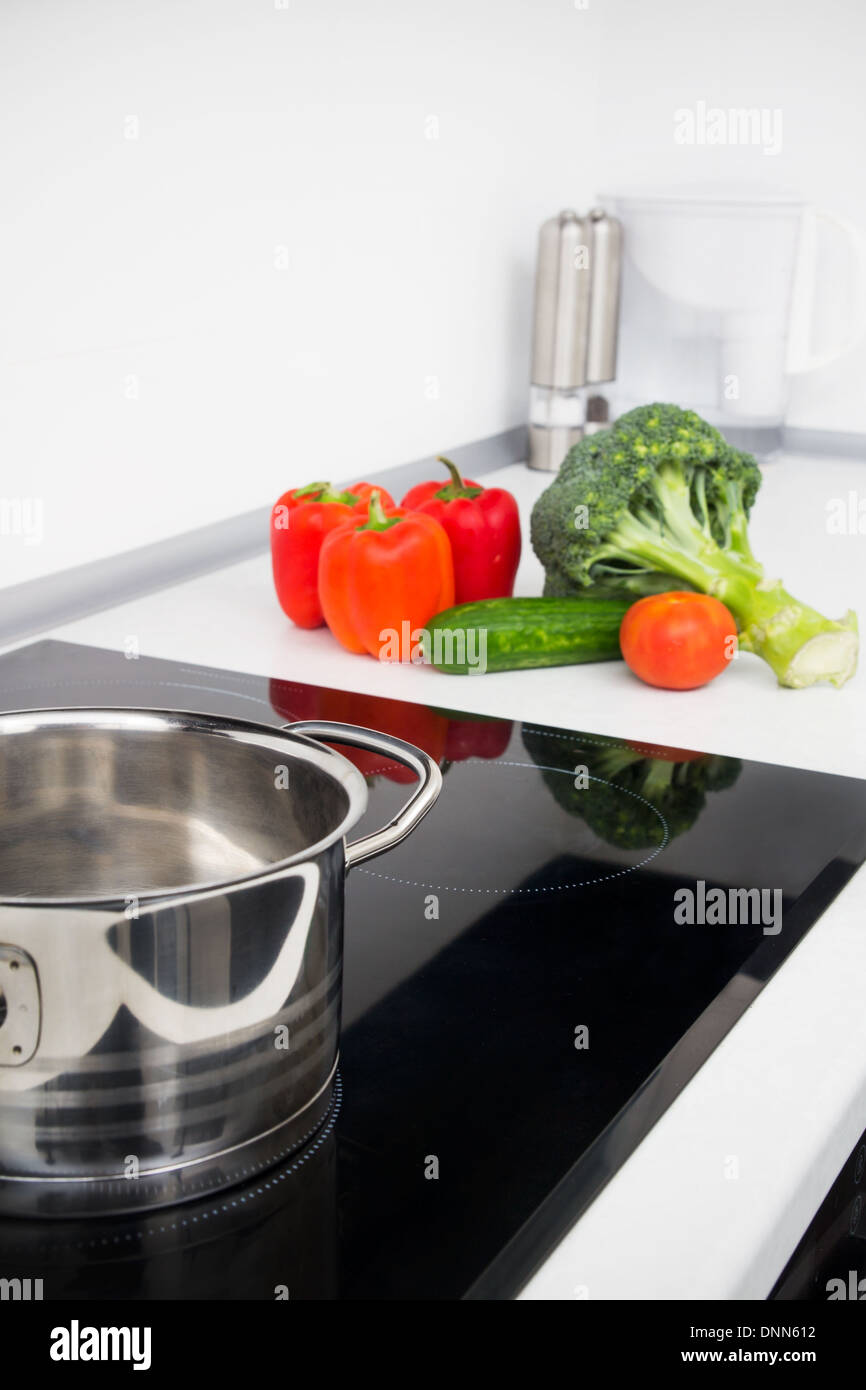 Pentola e verdure in cucina moderna con fornelli a induzione Foto Stock