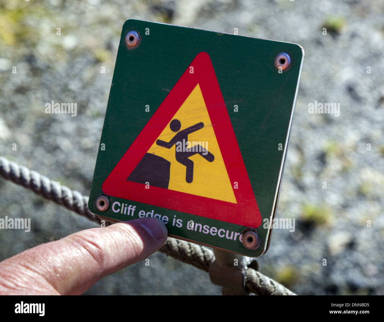 Puntare il dito in corrispondenza di rosso e di giallo segnaletica di pericolo con schema di persona sliiping o caduta che indica il rischio di caduta in Islanda Foto Stock