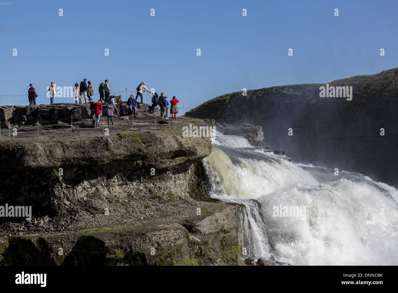 I turisti che si affaccia imponente cascata di Gullfoss (significato l'Golden cade') Islanda Foto Stock