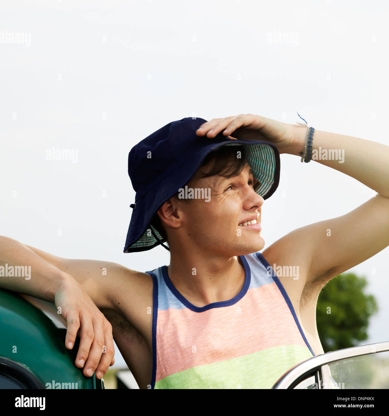 Giovane uomo appoggiato contro auto guardando qualcosa nella distanza Foto Stock