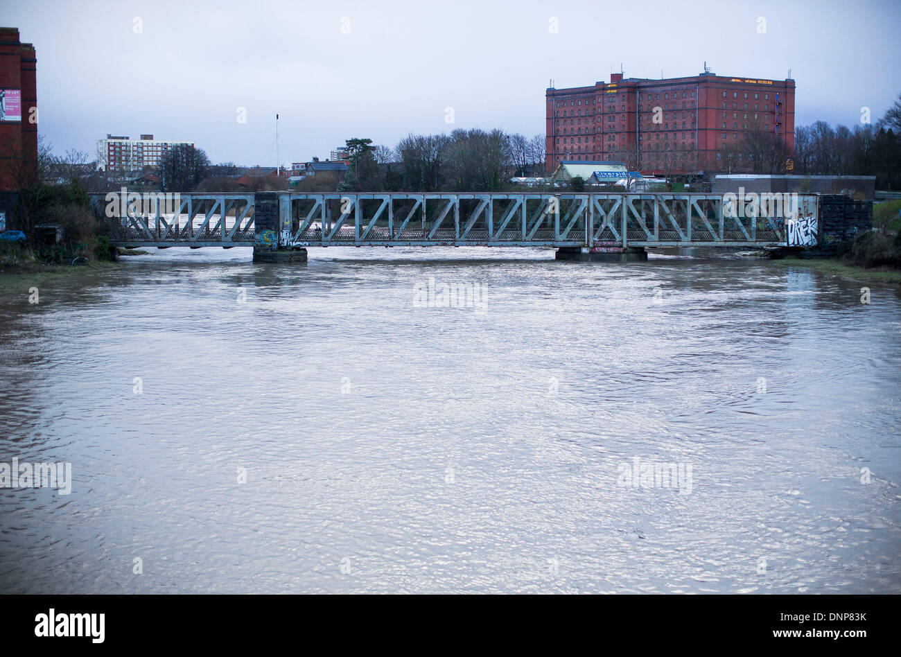 Bristol, Regno Unito. Il 3° gennaio 2014. Pendolari fanno la loro strada attraverso un ponte su un fiume gonfio Avon in Bristol seguenti alte maree e heavy rain. 3 gennaio 2014 Credit: Adam Gasson/Alamy Live News Foto Stock