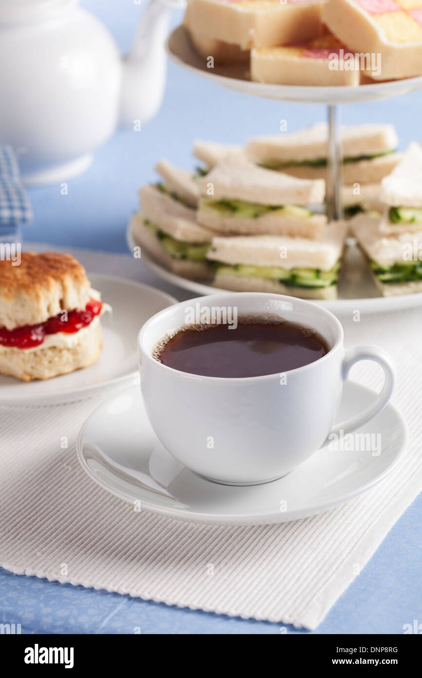 Tazza di tè con il cetriolo panini e focaccine in background. Foto Stock