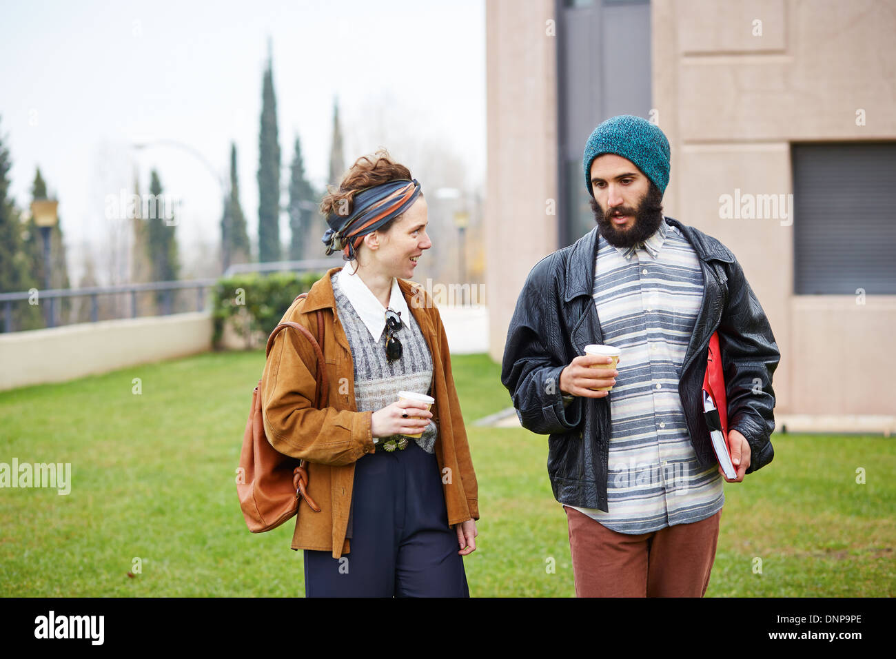 Hipster paio di parlare e di bere il caffè per andare al campus universitario Foto Stock