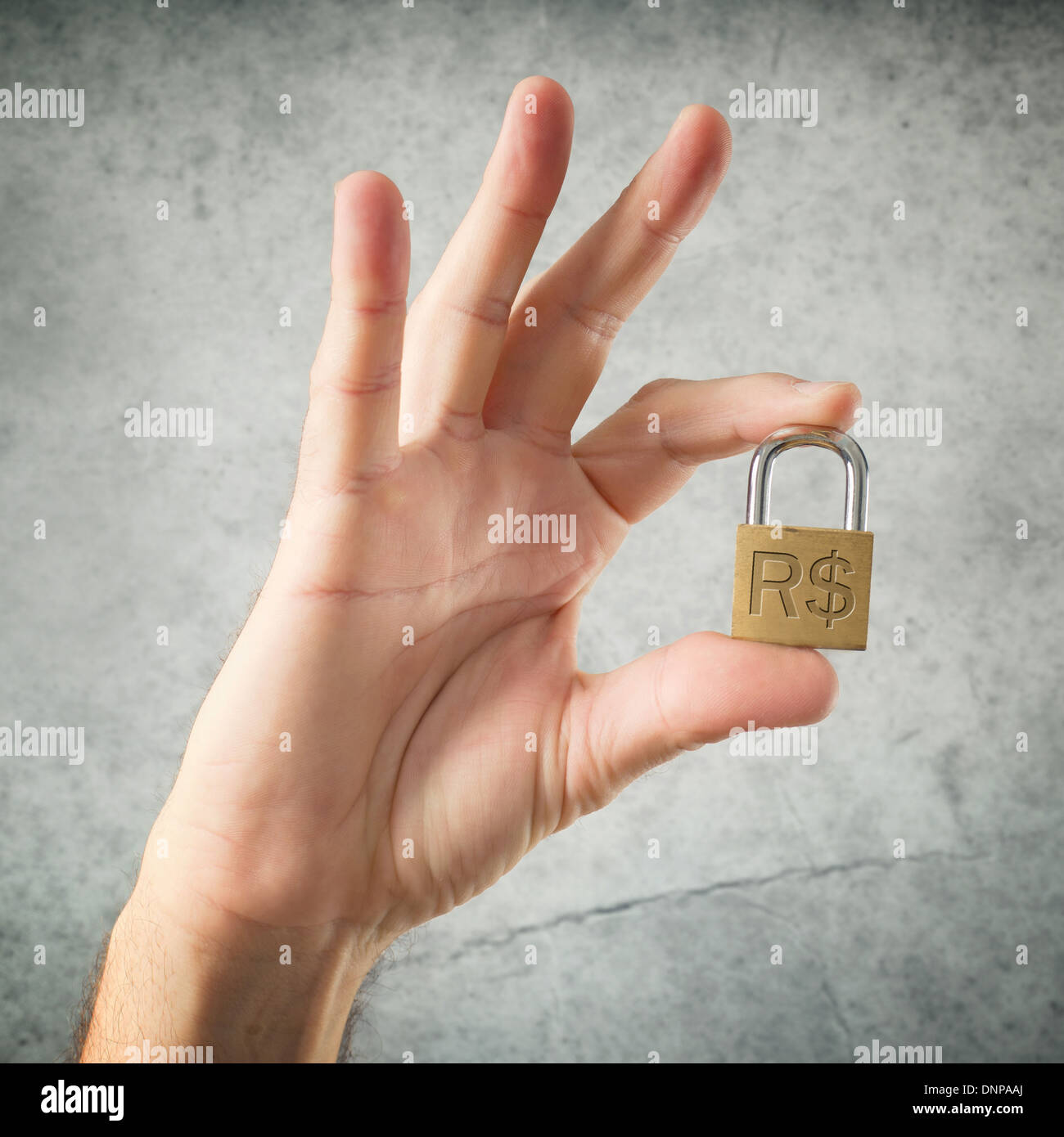 Mano che tiene il lucchetto con Real brasiliano il simbolo di valuta. Sicurezza e concetto di assicurazione. Foto Stock