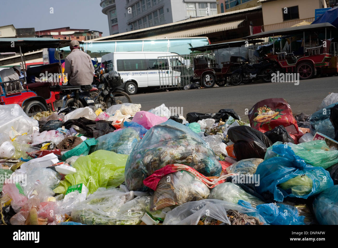 Un mucchio di marciume spazzatura e sacchetti di plastica sono sparsi su una strada di città vicino a una stazione degli autobus in Phnom Penh Cambogia. Foto Stock