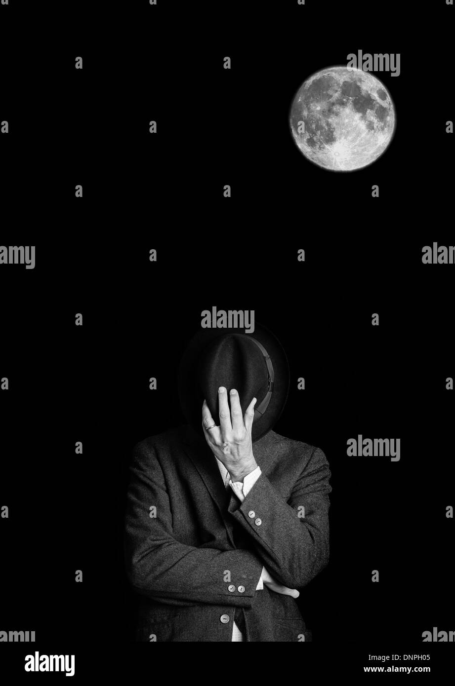 Immagine in bianco e nero di un uomo in una giacca con un cappello vintage nasconde la sua faccia con copia spazio sopra. Foto Stock