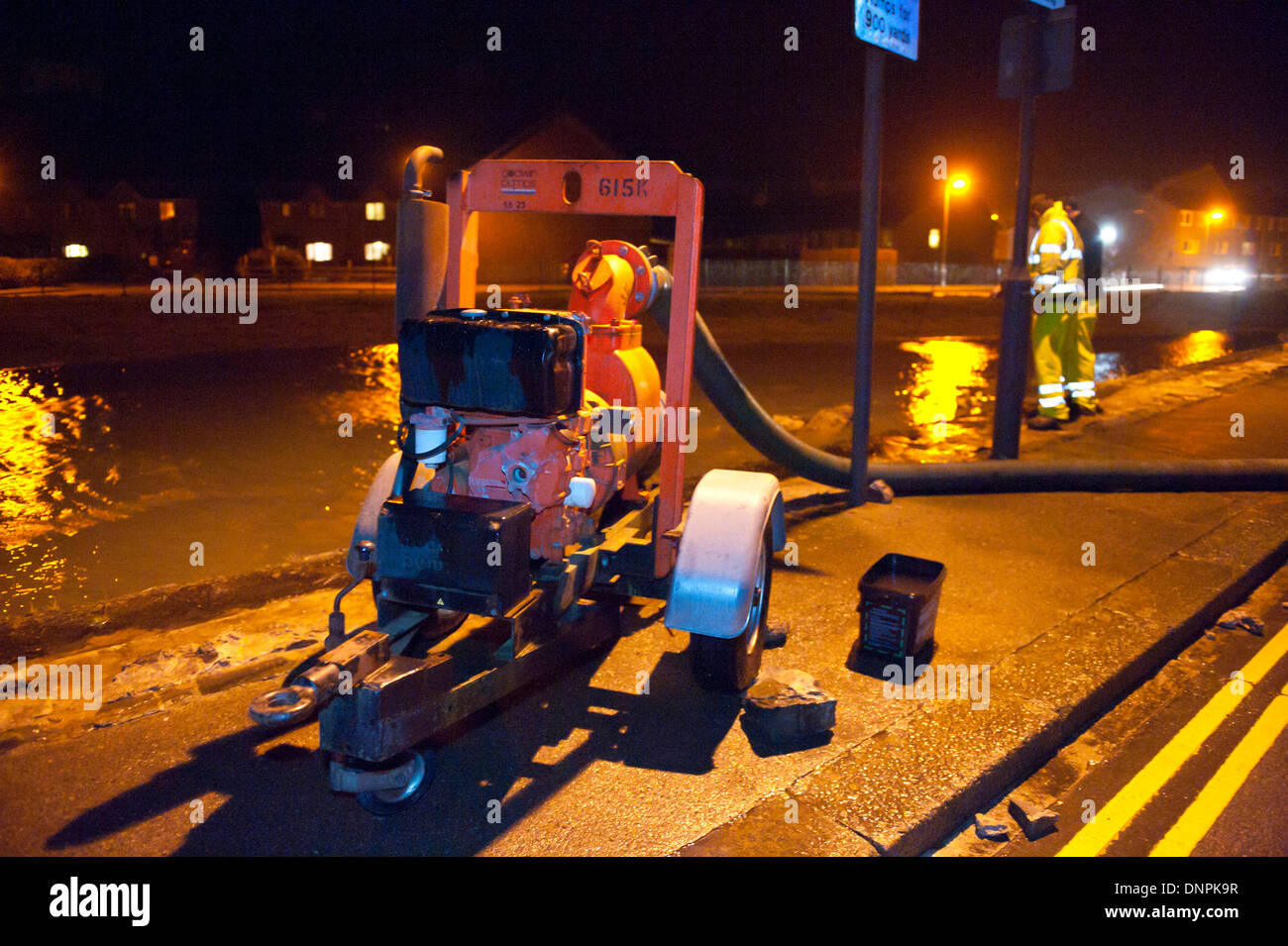 Blaenau Ffestiniog, Gwynedd, Wales, Regno Unito. Il 3° gennaio 2014. Consiglio operai della pompa acqua lontano da questa mattina le inondazioni. Persone riempire sacchi di sabbia per proteggere le loro case sul Tai'r Heli station wagon. Questa mattina le onde ad alta marea ha infranto il muro del mare dando scarsa protezione da tonights alta marea a apprroximately 22.00h. Con oltre 500 alluvione avvisi e allarmi su tutto il territorio nazionale agenzia per l'ambiente ha messo in guardia le persone a essere preparati per proteggere se stessi e le loro case e a rimanere ben indietro dalla high water mark sui litorali. Credito: Graham M. Lawrence/Alamy Live News. Foto Stock