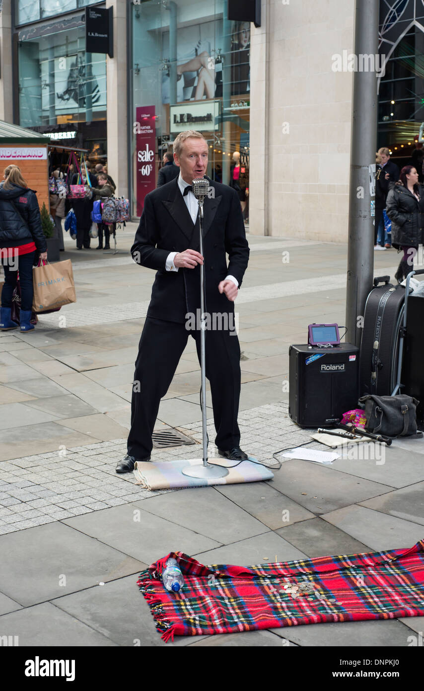 Ben vestito uomo cantano per le strade di Manchester a Natale Foto Stock