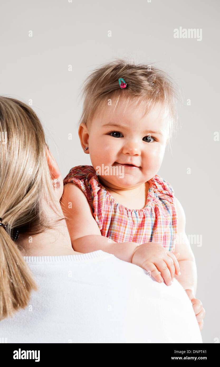 Ritratto di bambina cerca su madre della spalla, Studio Shot Foto Stock