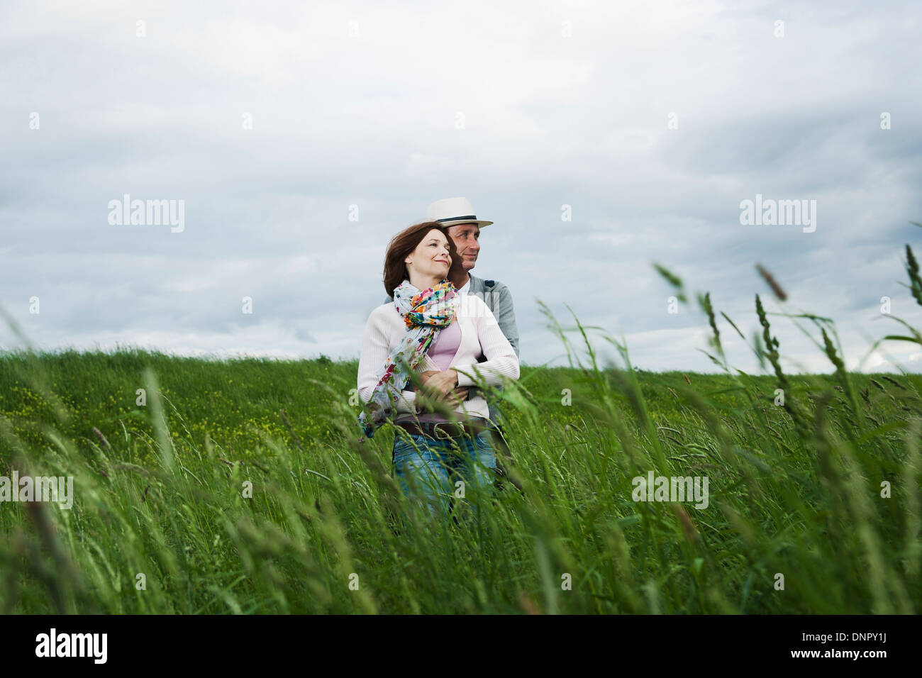 Coppia matura in piedi nel campo di erba, abbracciando, Germania Foto Stock