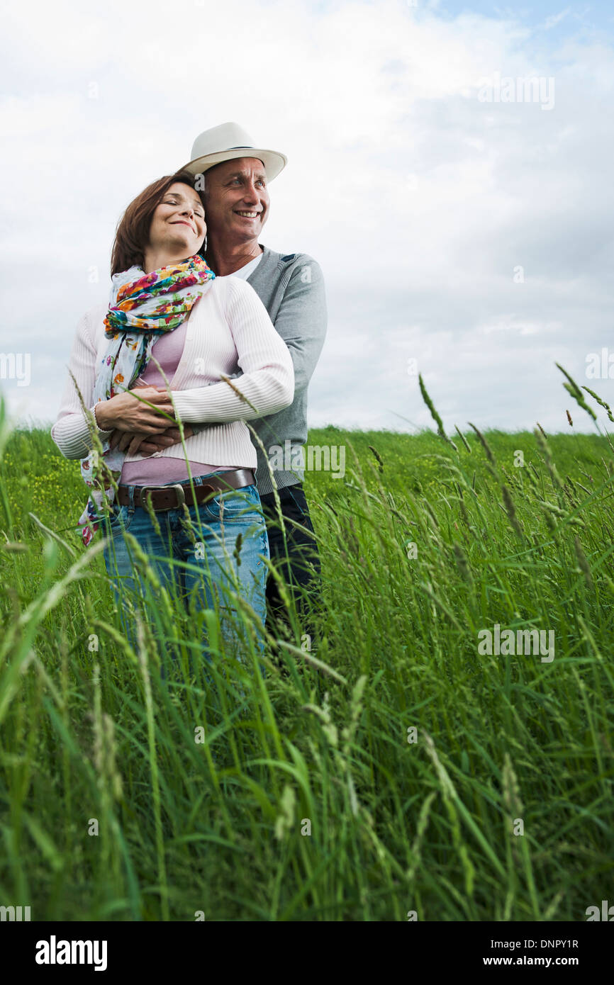 Ritratto di Coppia matura in piedi nel campo di erba, abbracciando, Germania Foto Stock