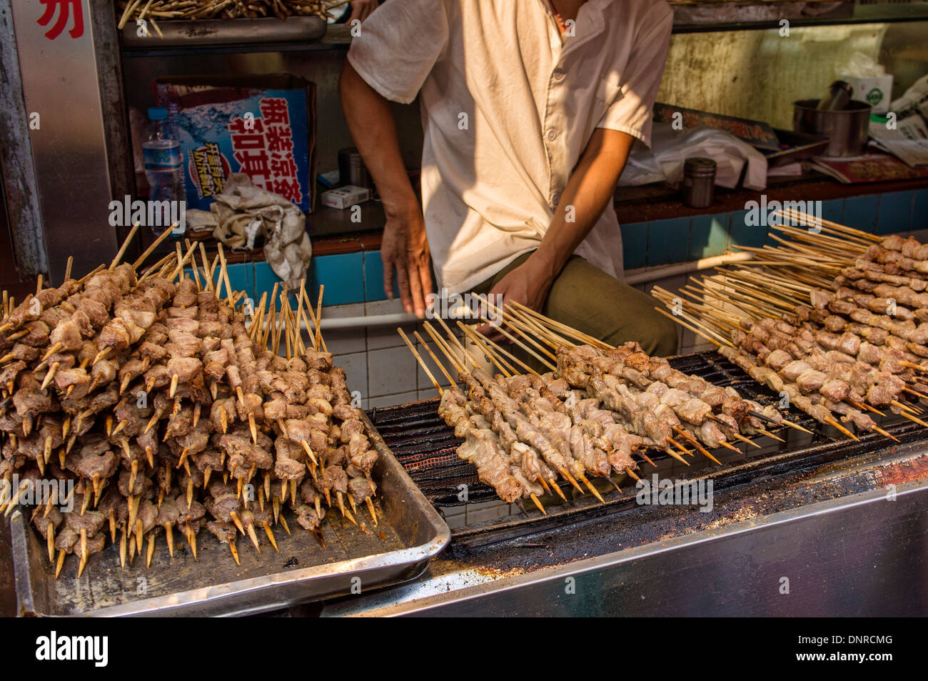 Uomo di torrefazione di shish kebab in Via Wangfujing di Pechino, Cina Foto Stock