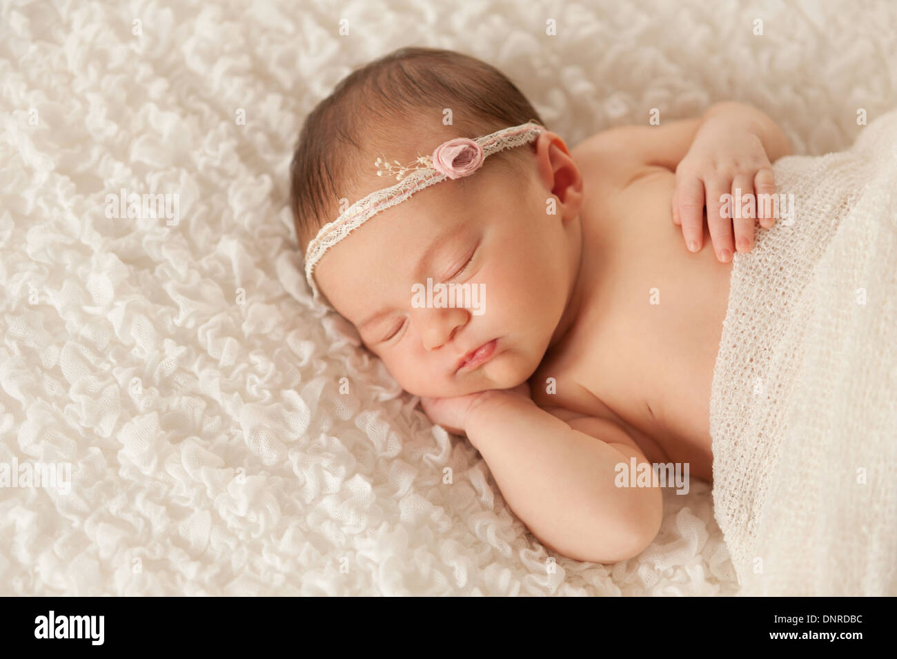 Sleeping neonato bambina indossa un archetto di pizzo. Foto Stock