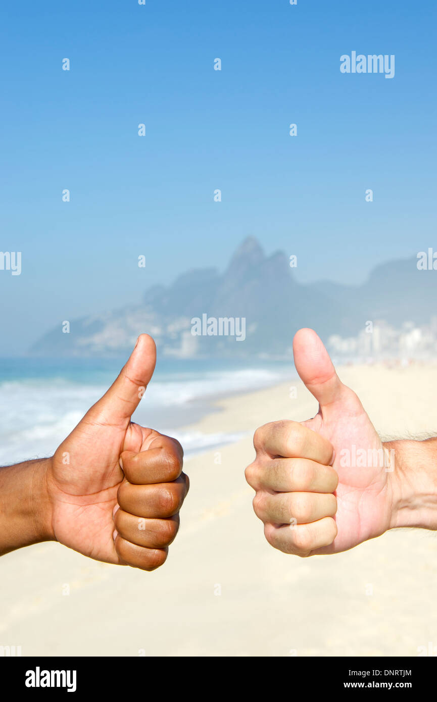 Diversità brasiliana due interracial Carioca pollice in alto sulla spiaggia di Ipanema di Rio de Janeiro in Brasile Foto Stock