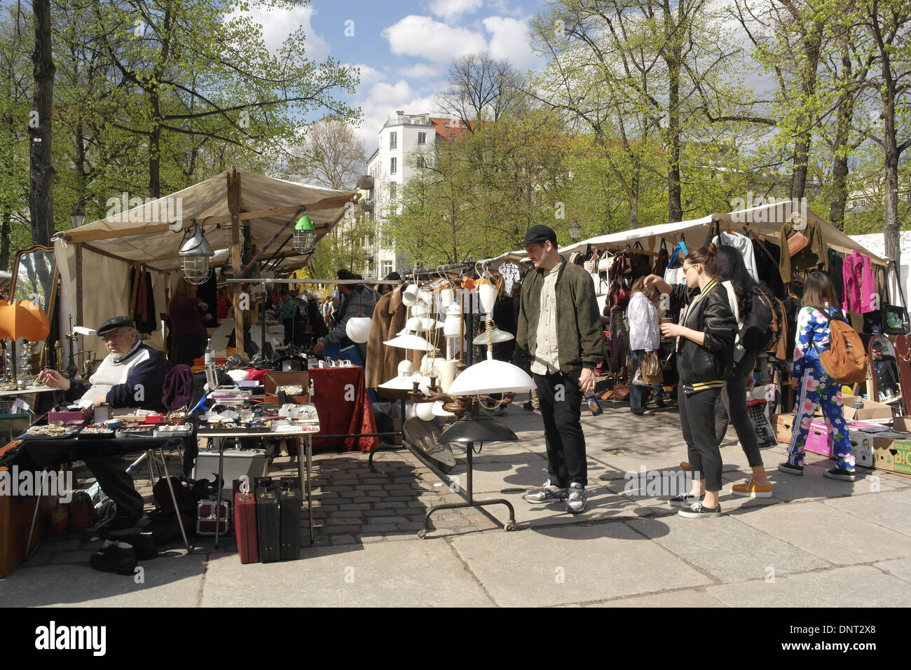 Sunny verdi alberi vista, persone in piedi da bancarelle di vendita gioielli e lampade Granseer Strasse, Arkonaplatz Mercato delle Pulci, Berlino Foto Stock