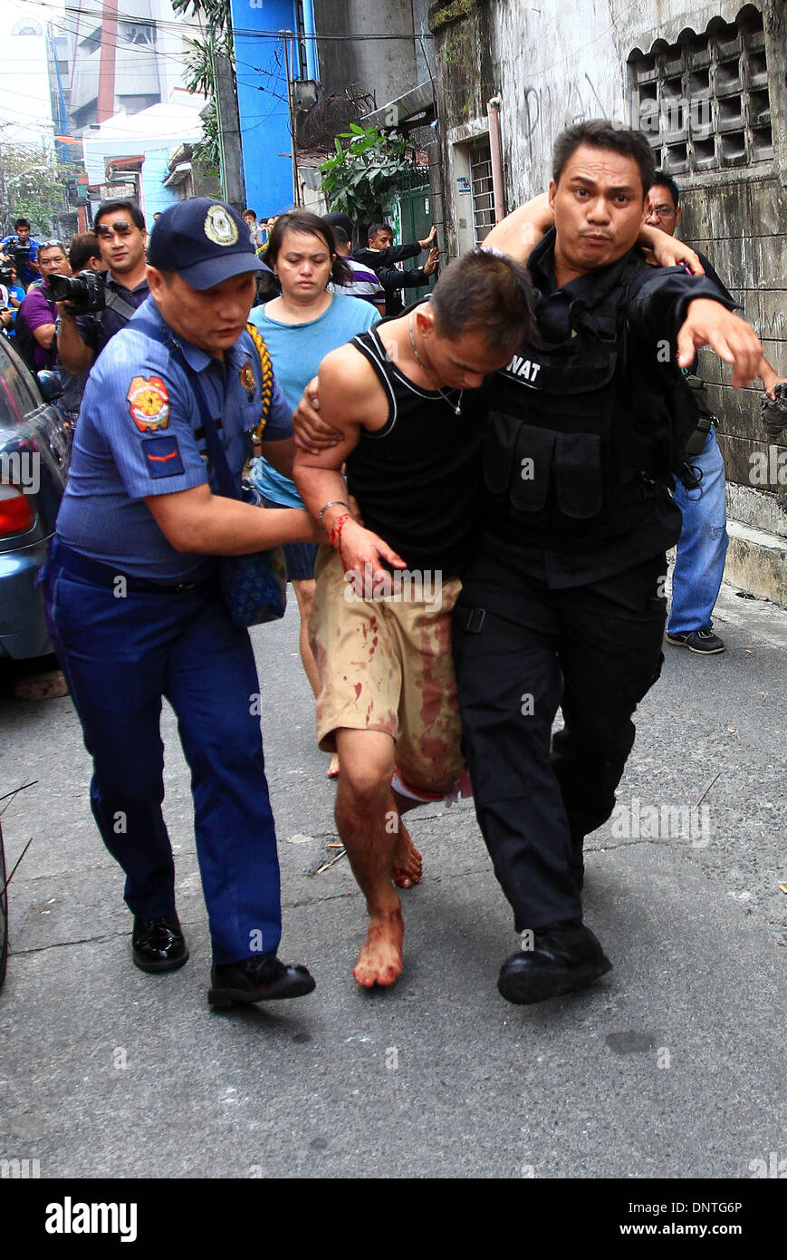 Quezon City, Filippine. Il 6 gennaio, 2014. Un ferito in ostaggio la vittima è portato da poliziotti dopo la crisi degli ostaggi in Quezon City, Filippine, Gennaio 6, 2014. Quattro persone tra cui un bambino sono rimasti feriti dopo essere stati presi in ostaggio dal sospetto per tre ore. Credito: Rouelle Umali/Xinhua/Alamy Live News Foto Stock