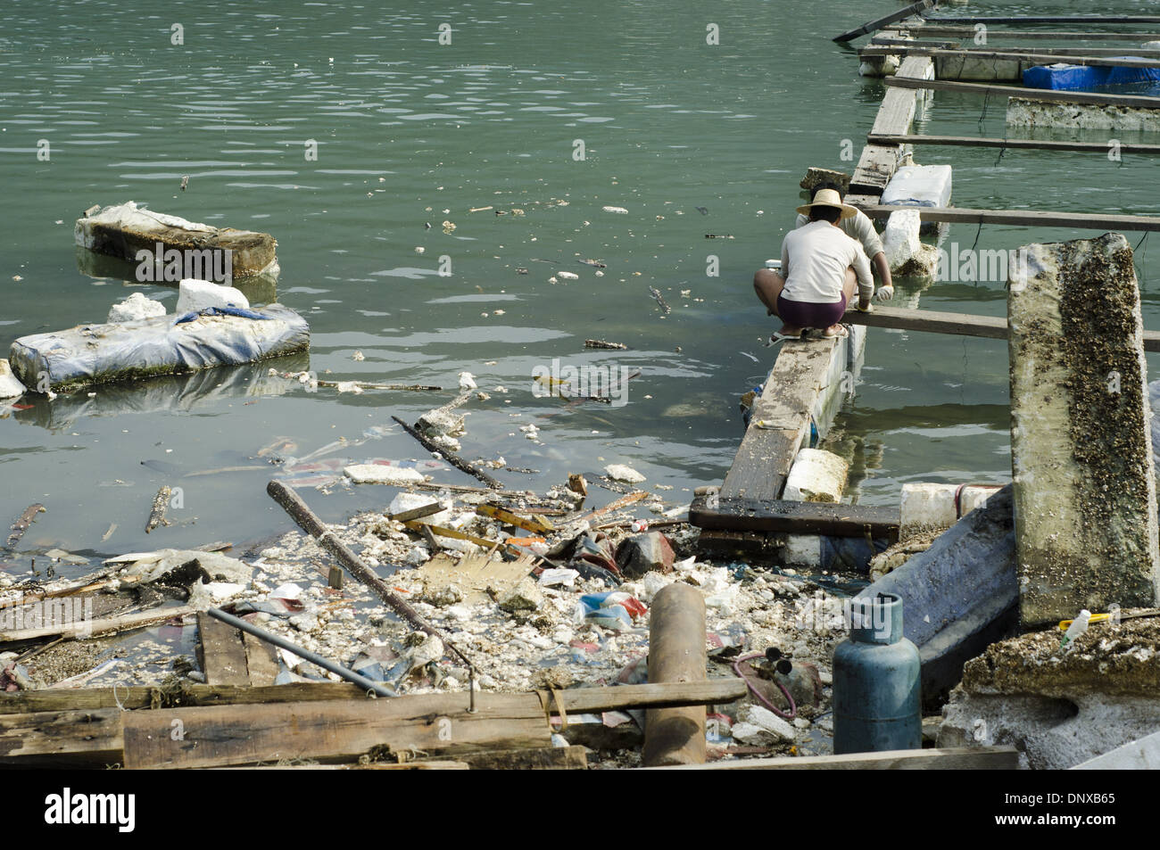 I pescatori e i lavoratori scaricano il legno tra mattoni di plastica e di styrofoam rotti e scartati, scatole e pile di imballaggio in un porto dove i pescherecci scaricano le loro catture. L'inquinamento è così esteso che alcune navi sono bloccate, incapaci di muoversi. Le aziende di pesca cinesi fanno inoltre ampio uso di scatole di polistirolo, dispositivi di galleggiamento e imballaggi che provocano danni ambientali e inquinano il mare e gli oceani, in quanto si rompe su e giù il nickel maltempo o a causa di uno smaltimento disattento. © Olli Geibel Foto Stock