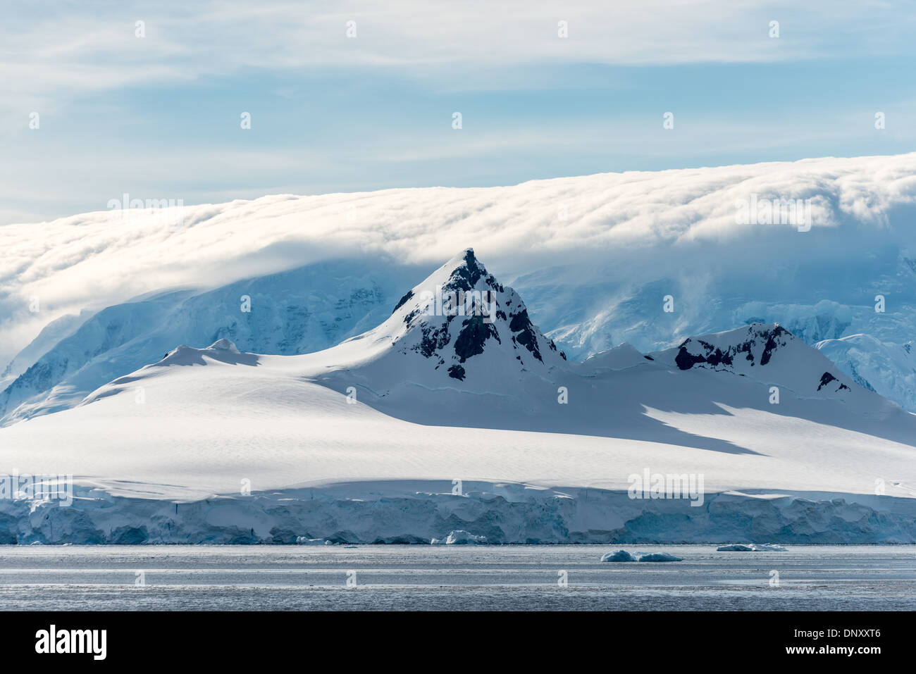 Antartide - un picco scosceso sorge sopra la montagna surround, mentre in background le nubi oscure un ancor più alti di gamma della montagna in stretto di Gerlache sulla penisola antartica. Foto Stock