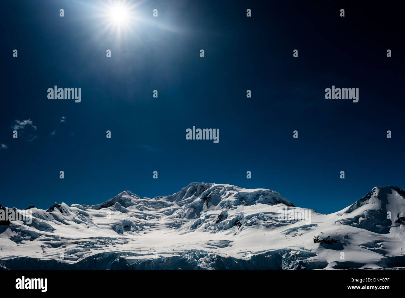 Montagne innevate Antartide // montagne innevate in Antartide contro un cielo blu profondo con il sole. Foto Stock