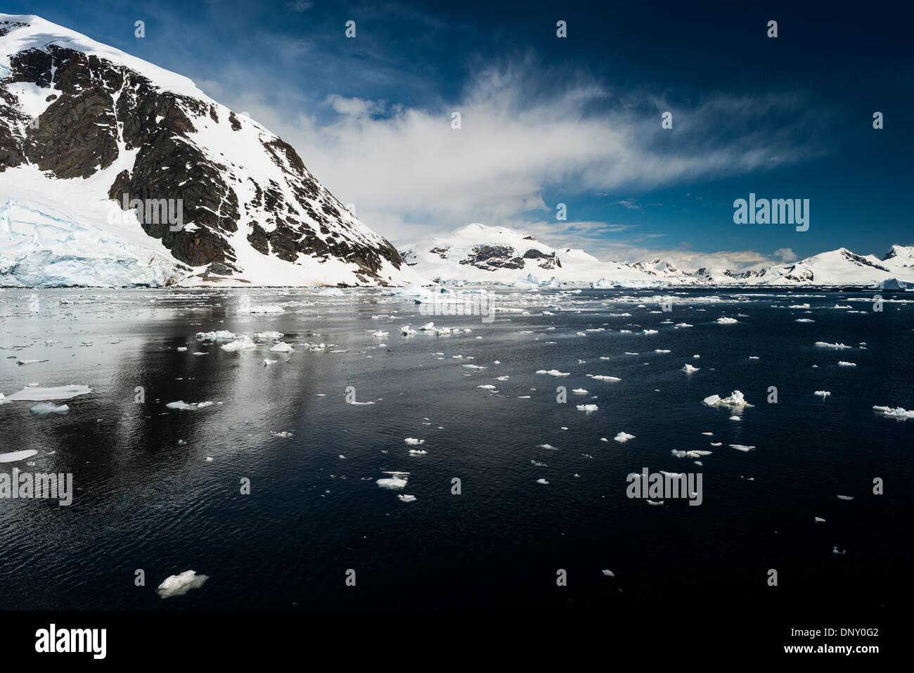 Antartide - paesaggio panoramico sulla penisola Antartica, con piccoli blocchi di ghiaccio galleggiante sull'acqua in primo piano e le montagne sullo sfondo. Foto Stock