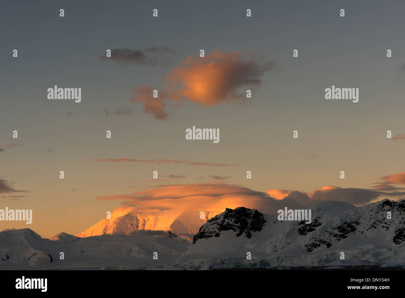 Antartide - un piccolo soffio di cloud e una montagna catturare i raggi del sole al tramonto a Paradise Harbour, l'Antartide. Foto Stock