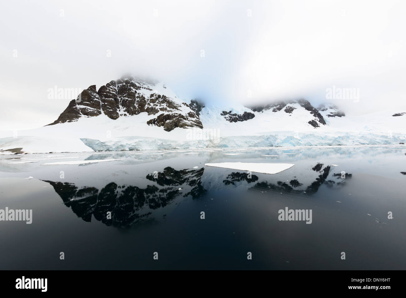 Antartide - Montagne parzialmente coperto di ghiaccio e neve sono riflesse su ancora perfettamente simili a specchio acque nel canale di Lemaire sulla costa occidentale della penisola antartica. Foto Stock