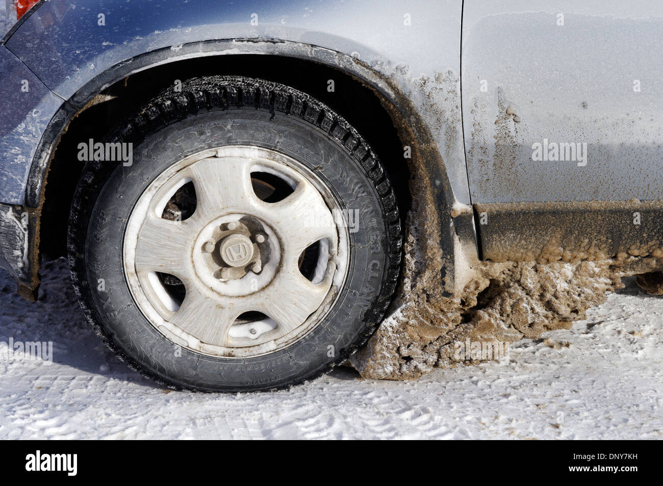 Un enorme blocco di ghiaccio congelato sotto la ruota di una vettura in inverno canadese Foto Stock