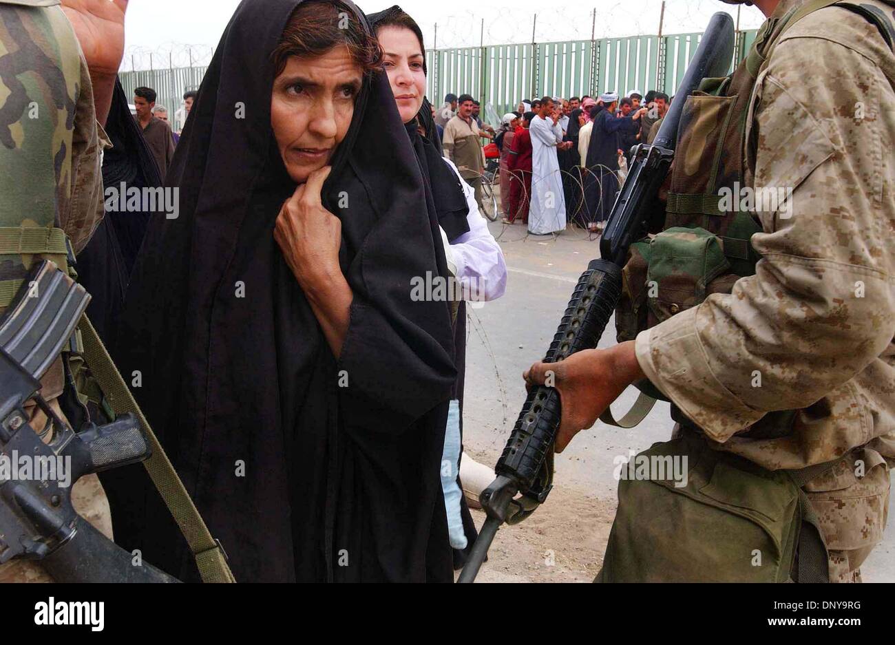 (Ripubblicato 4/17/2005, G-5) (SignOn Gallery 10/21/2003) NC TIKRIT x001 ........... Aprile 15, 2003, Tikrit, Iraq ......... ''Esigenza fotografica photoshop regolazione'' ........ Una donna araba donna fa il suo modo in passato negli Stati Uniti Marines checkpoint come lei ritorna a casa loro a Tikrit. Di Tikrit considerato essere uno degli ultimi forte iracheno tenere ora è sotto il controllo della forza di coalizione Foto Stock