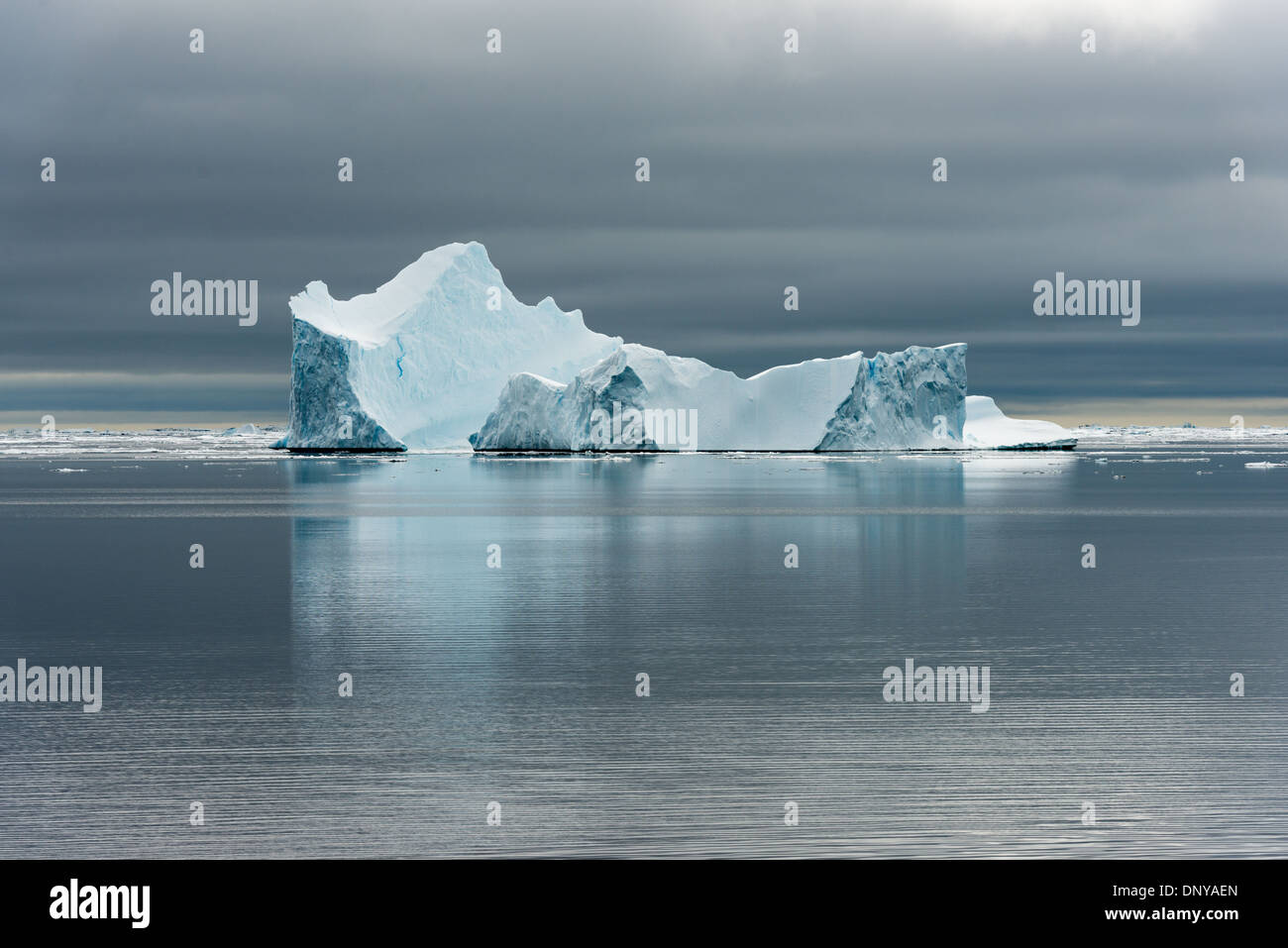 Antartide - Antartide Iceberg la sottile la colorazione si staglia contro le acque calme e cieli grigi vicino Galindez Island in Antartide. Foto Stock